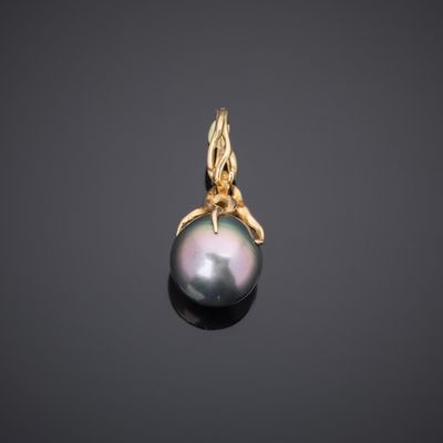 a black pearl and gold pendant on a black background