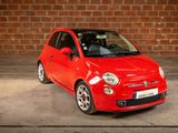 the small red car is parked in front of a brick wall