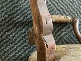 a close up of a wooden chair with a tan upholstered seat