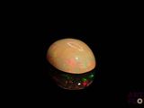 an image of a white opal with green and red lights
