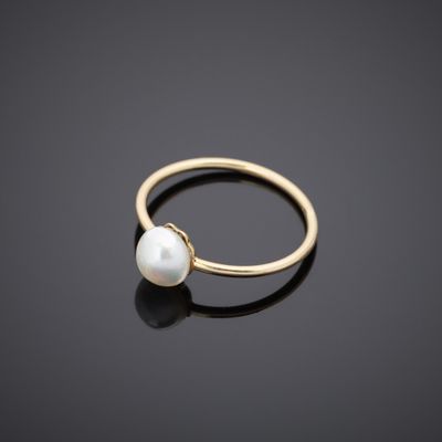 a gold ring with a white pearl on a black surface