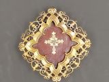a close up of a gold and red broochle with a cross on it