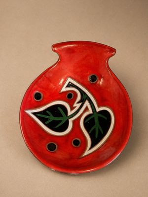 un vase rouge orné d'un motif en noir et blanc