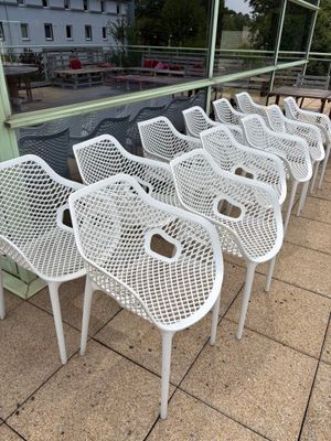 de nombreuses chaises en plastique blanc alignées sur le trottoir