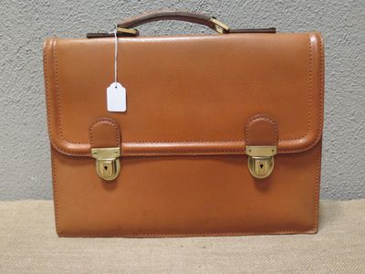 une mallette en cuir marron à laquelle est accrochée une étiquette de prix