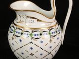 a white pitcher with blue flowers on it on a black background