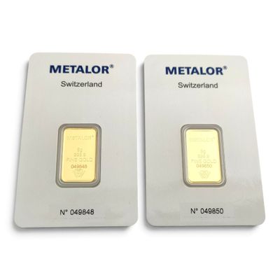 Deux lingots d'or sont posés côte à côte sur une surface blanche