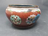 a red vase with flowers on it on a table