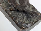 statue of a dog sitting on top of a rock on a white surface
