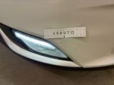 the front end of a white car with a sticker on it ' s bumper