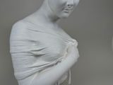 a white statue of a woman with a flower in her hair