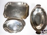 deux plateaux en argent et une cuillère en argent posés sur une surface blanche