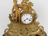 a gold clock with a statue on top of it