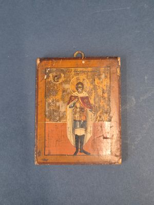 une vieille icône en bois représentant un homme tenant une croix sur un fond bleu