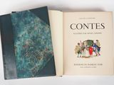 un livre ouvert posé sur une table blanche, à côté d'un livre bleu