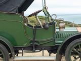 an old green car parked on the side of the road