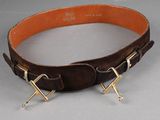 brown leather belt with two metal studs on a gray surface