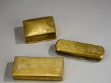 trois lingots d'or posés les uns à côté des autres sur une surface blanche