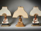 trois lampes ornées de statues de Bouddha, posées sur une table