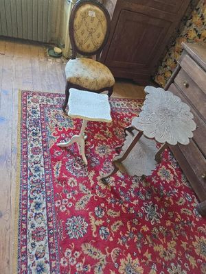 un tapis rouge posé à même le sol dans une pièce où se trouvent une chaise et une commode