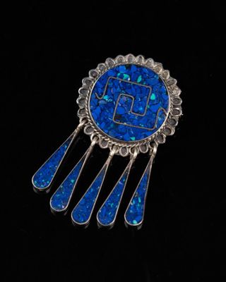 un gros plan sur une broche bleue ornée d'incrustations d'argent