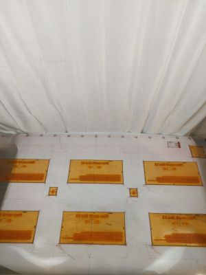 une feuille de papier blanche posée par terre, sous une autre feuille de papier blanche