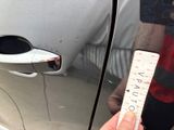a person holding a ruler in front of a car door
