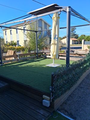 a green lawn with a wooden bench and umbrellas on it