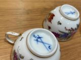 two tea cups sitting on a table next to each other