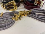 three belts and a belt with a gold buckle on a table