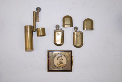 un assortiment d'objets en laiton, comprenant notamment un briquet, un étui à briquet et un briquet
