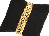 un gros plan d'un bracelet plaqué or posé sur un coussin noir