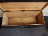 a small wooden chest with a lid open on a carpeted floor