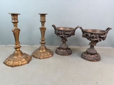 Trois bougeoirs en laiton ancien sont posés sur une table
