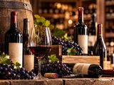 bottles of wine and glasses of wine sit on a table in front of a barrel