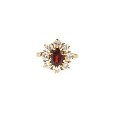 gros plan d'une bague avec une pierre rouge entourée de diamants blancs