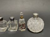 three small glass bottles with silver lids and a silver stopper