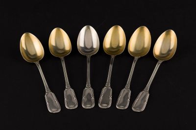 six silver and gold spoons on a black background