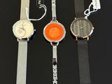 three watches are sitting on a black surface with tags attached to them