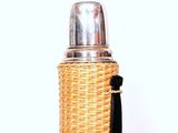 a wicker bottle with a black handle on a table
