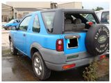 a blue car parked in a parking lot with a tire cover on it ' s back
