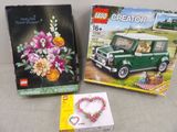 Deux boîtes de Lego sont posées sur une table, à côté d'un bouquet de fleurs.