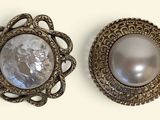 pair of silver and mother of pearl brooches on a white background