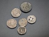 six ancient roman coins on a table with a black background