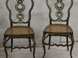 pair of black and gold painted chairs with wicker seats