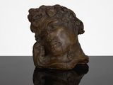 a bronze sculpture of a woman ' s head on a black surface