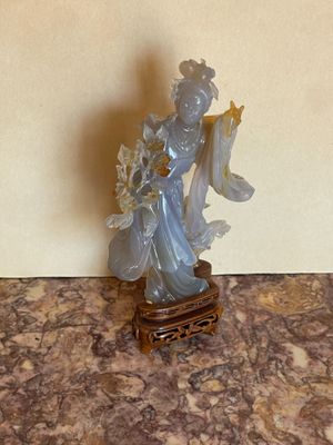 une statue représentant une femme tenant un éventail, posée sur une table