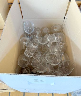 une boîte remplie de gobelets en plastique vides posée sur un sol carrelé
