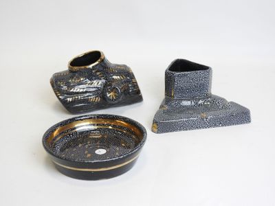 three pieces of pottery sitting on a white surface