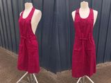 pair of red aprons on a mannequin stand in front of a blue wall